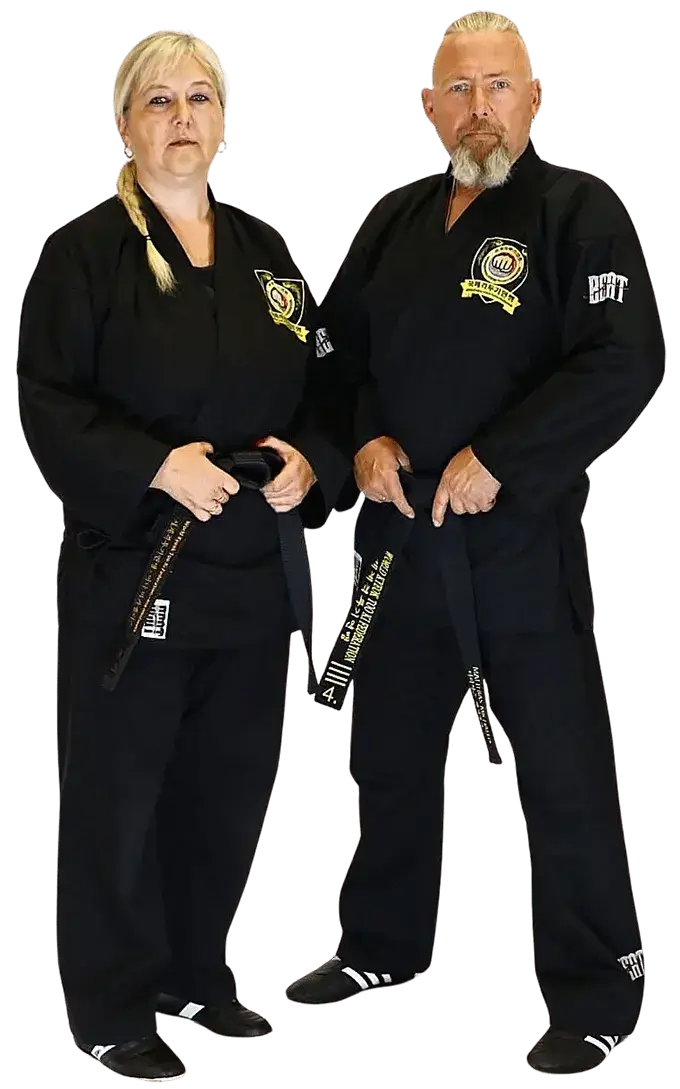 Kampfkunstschule Korean Fighters Werl - Grossmeister Matthias Michaelis und Meisterin Ina Michaelis Großmeister Matthias Michaelis und Meisterin Ina Michaelis der Kampfkunstschule Korean Fighters Werl stehen nebeneinander in schwarzer Kampfkunstkleidung mit Vereinsabzeichen und halten ihre Gürtel/Gradierung sichtbar in den Händen – Studioaufnahme, neutrales Setting.