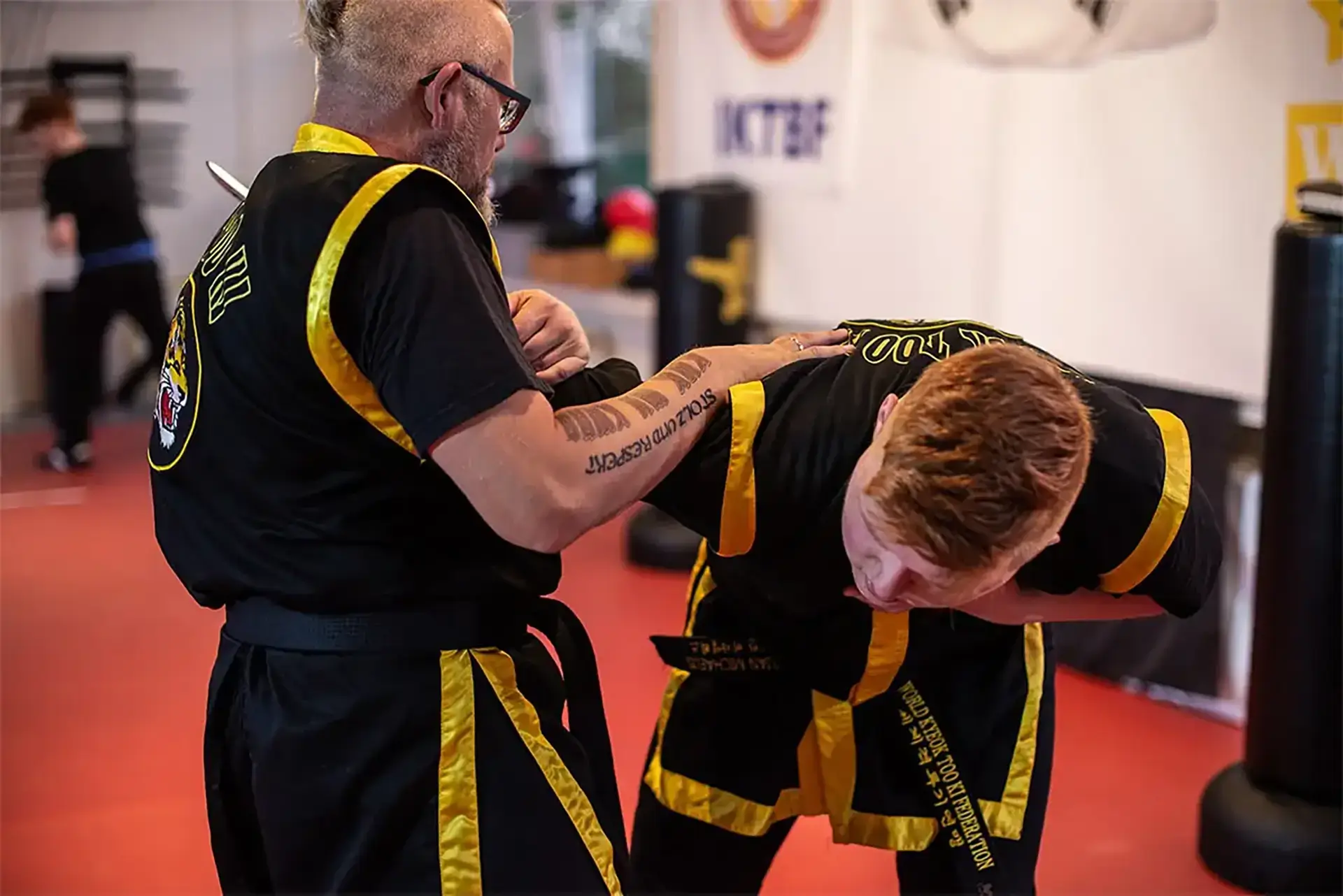 Kampfkunstschule Korean Fighters Werl - Kyeok Too Ki - Kachel Korean Fighters Werl – Kyeok Too Ki: Instructor zeigt Messerabwehr und Kontrolle, führt den Partner über Arm- und Schulterhebel aus dem Gleichgewicht; Trainingsmesser und Trainingsbereich der Schule im Hintergrund.
